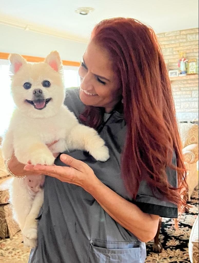 Soraya smiling as she holds a small cream Pomeranian